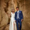 Blauer Bräutigamanzug mit hellgrauer Weste und Krawatte – stilvoller Hochzeitslook in Kombination mit weißem Brautkleid in Felskulisse.