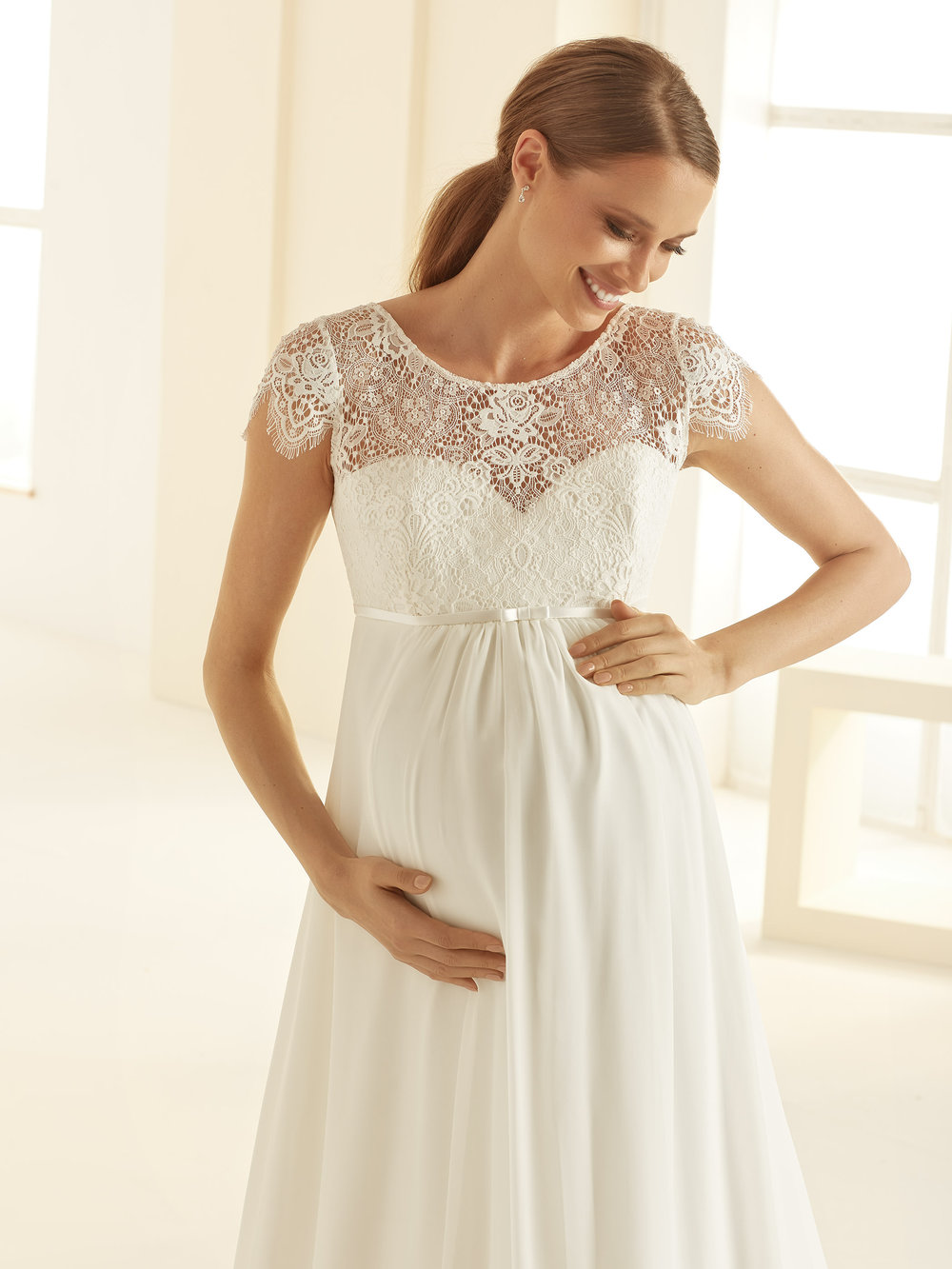 Detailaufnahme des Brautkleids mit feiner floraler Spitze, zarten Trägern und halbtransparentem Mieder.