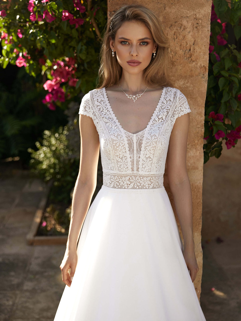 Detailansicht des Boho Brautkleids mit floraler Spitze, V-Ausschnitt und figurbetonter Taillenpartie.