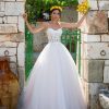 Prinzessinnen-Brautkleid mit Schnürung und Tüllrock, romantische Aufnahme vor einem Steinbogen mit floralen Akzenten.
