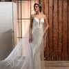 Modernes Fit & Flare Brautkleid mit schmalem Schnitt, tiefem V-Ausschnitt und Spaghettiträgern – aufgenommen im eleganten Loft-Ambiente mit langem Schleier.