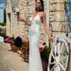 Fit & Flare Brautkleid mit Spitze, tiefem Rückenausschnitt und figurbetontem Schnitt – sommerliche Kulisse mit Steinwand.