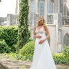 Umstandsbrautkleid mit floraler Spitze und weitem Rock vor historischer Kulisse