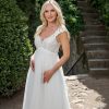 Detailaufnahme vom Spitzenoberteil eines eleganten Umstandsbrautkleides in Gartenumgebung
