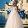 Prinzessin Brautkleid mit Tüllrock, tiefem Rückenausschnitt und Spitzenoberteil – Braut posiert an malerischem Hafen mit maritimer Kulisse.
