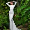 Fit & Flare Brautkleid mit langen Ärmeln und tiefem Rückenausschnitt, aufgenommen in tropischer Kulisse.