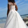 Rückansicht des Brautkleids mit halbtransparentem Rückenteil, Spitze und fließender Schleppe aus Tüll am Meer.