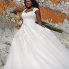 Curvy Braut in weißem Brautkleid mit romantischer Spitze, Herzausschnitt und ausgestelltem Tüllrock vor Felswand mit orangefarbenem Moos.